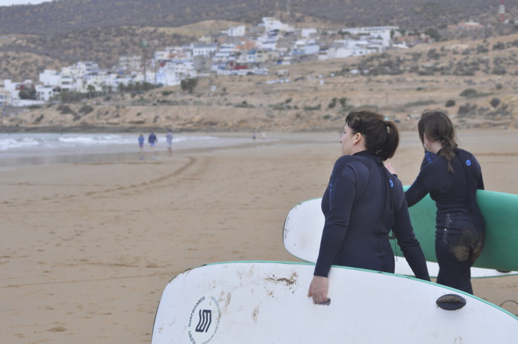 Beginner surfer catching small waves at Panorama Beach, one of the best Taghazout surf spots.